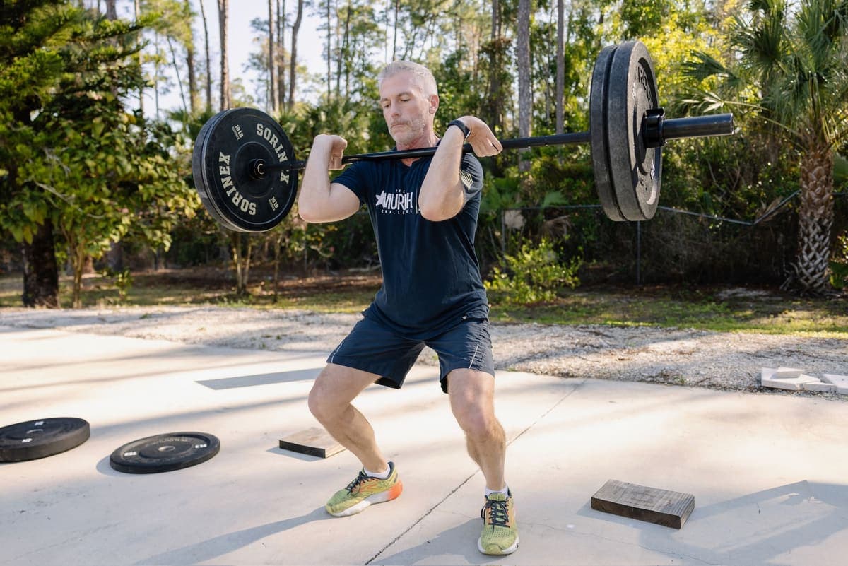 Adult client front-squatting with confident form at a Shred Shed outdoor session